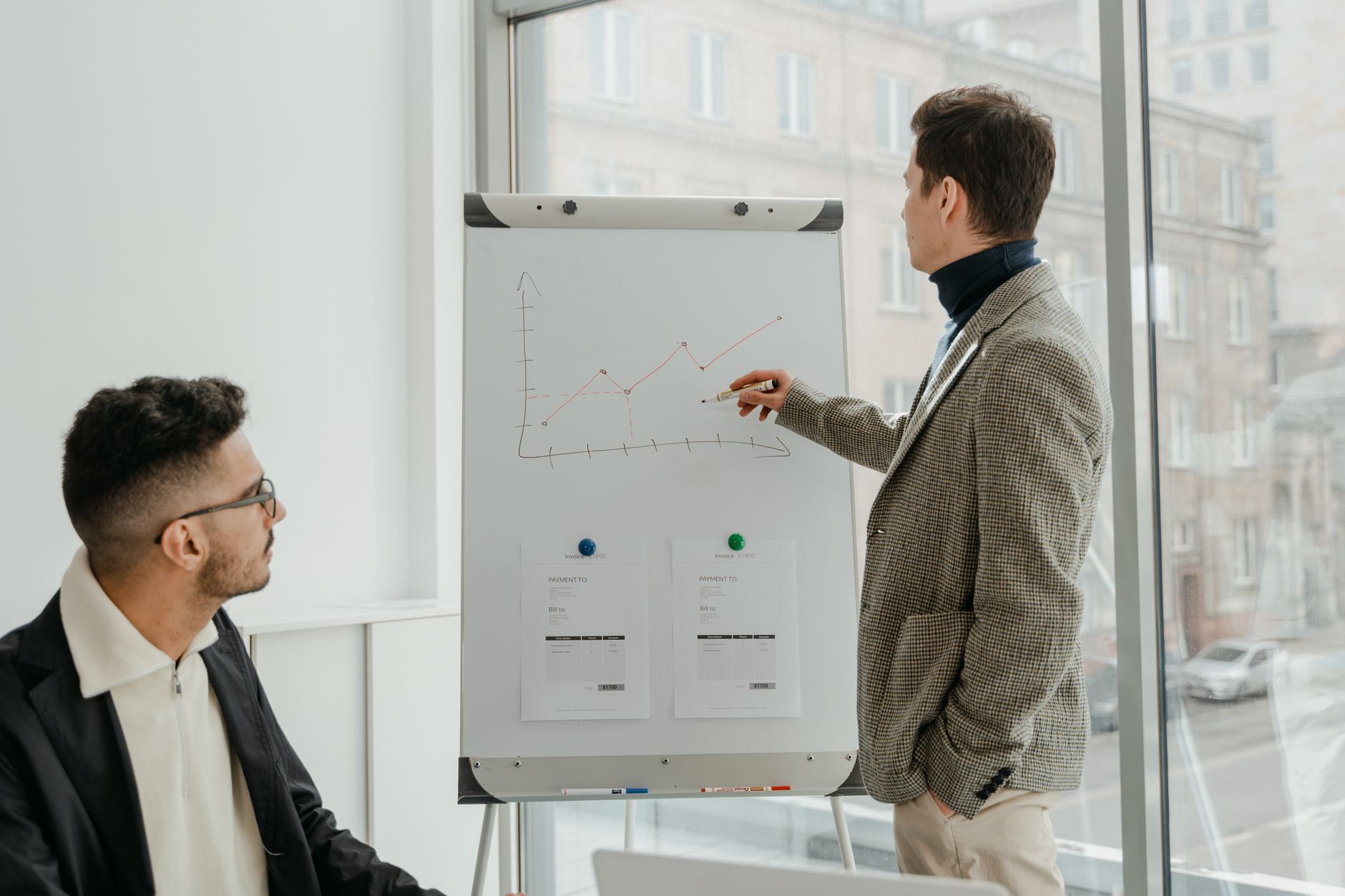 Two professionals examining graphs during an office presentation. — Allan Boomer on the Board: Steering Nonprofits Towards Fi