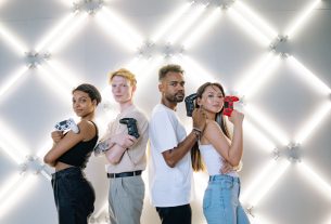 Four diverse friends posing confidently with game controllers against a modern LED backdrop. — Enjoy Continuous Slot Entertai