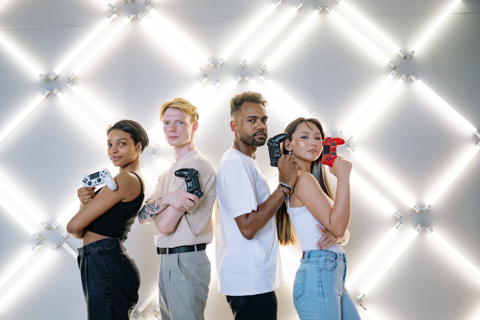 Four diverse friends posing confidently with game controllers against a modern LED backdrop. — Enjoy Continuous Slot Entertai