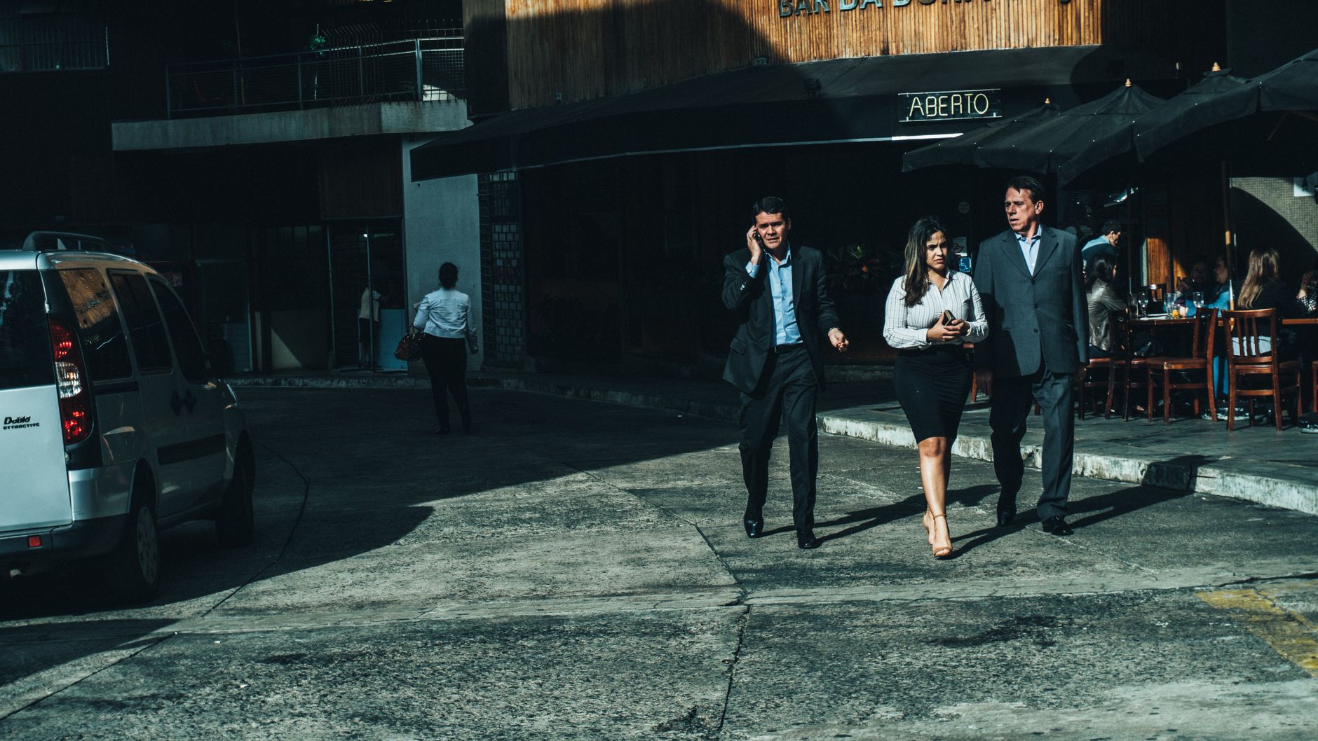 Three business professionals walk along a city street outside a cafe. — From Passion to Progress: The Journey of Rose Sarfo
