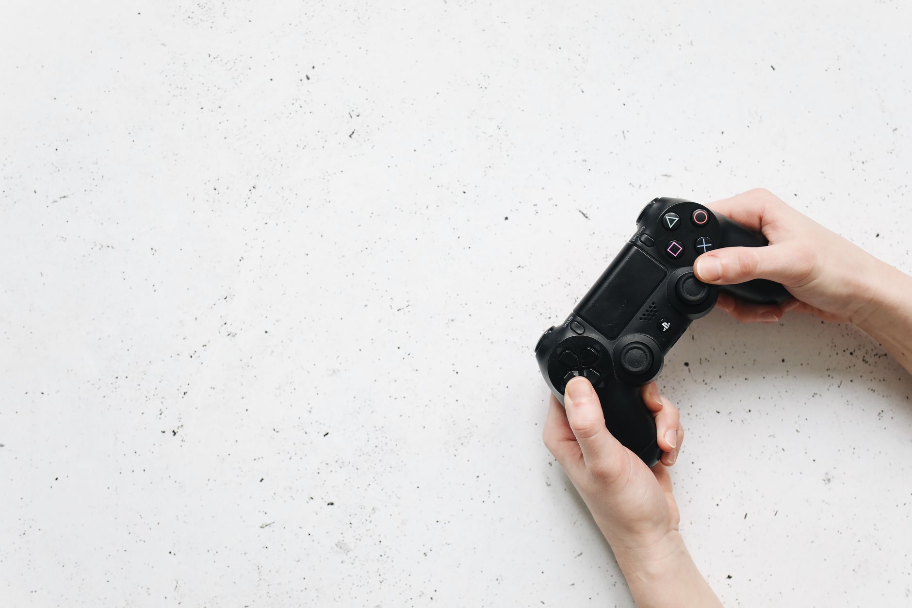 Close-up of hands holding a black game controller on a white background. — How TAG Grading Stands Out from PSA in Accuracy an
