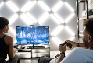 Two adults are having fun playing video games in a stylish, modern living room with LED lighting. — Join the Best Direct Bacc
