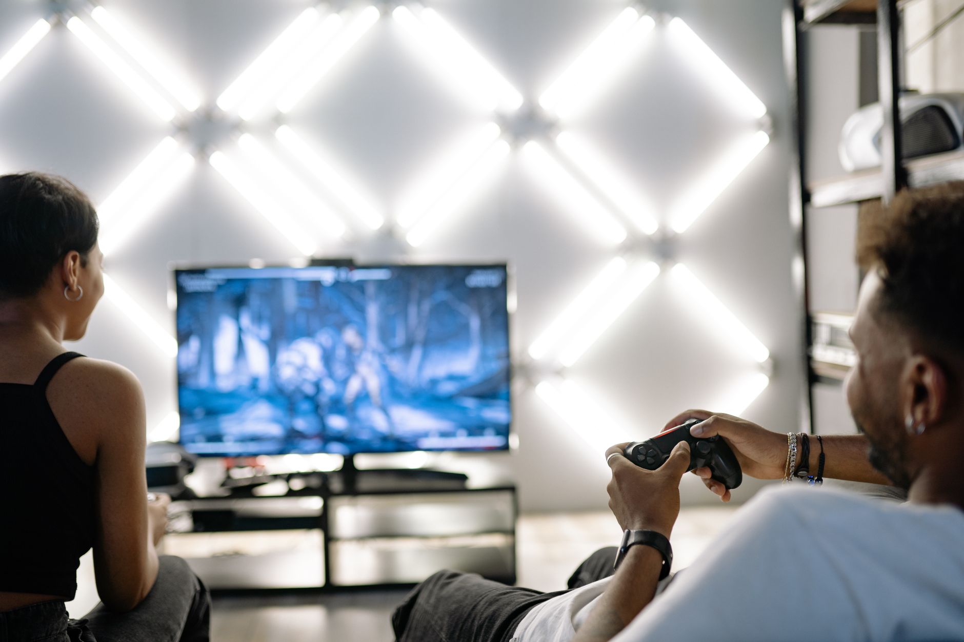 Two adults are having fun playing video games in a stylish, modern living room with LED lighting. — Join the Best Direct Bacc