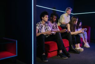 Teenagers enjoying video games together on a vibrant red couch in a modern gaming room. — Real-Time Results and Odds Come Sta