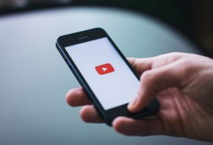 Close-up of a hand holding a smartphone displaying the YouTube app on the screen. — Stream2Watch: Where to Find 100% Legal Of