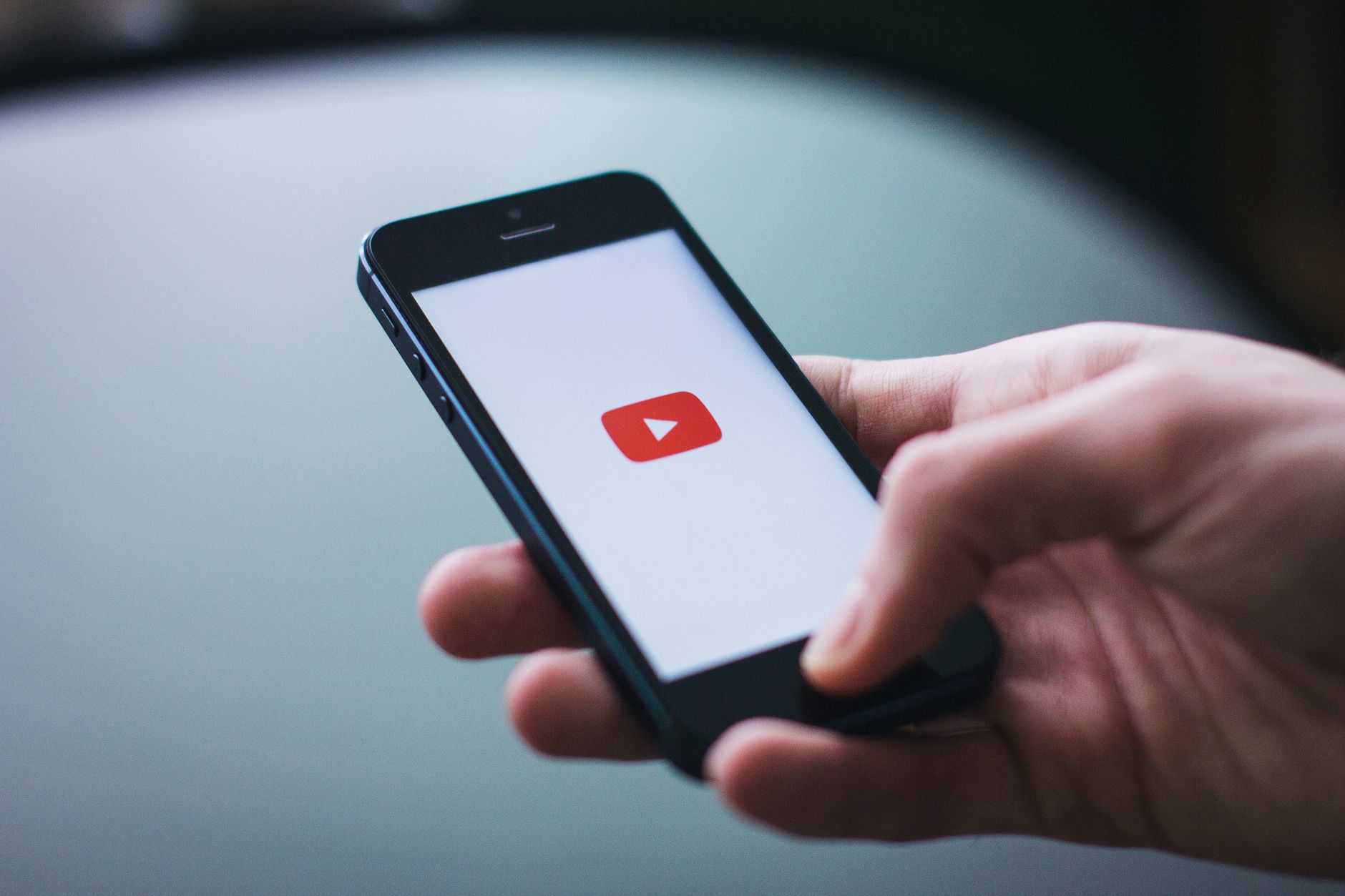 Close-up of a hand holding a smartphone displaying the YouTube app on the screen. — Stream2Watch: Where to Find 100% Legal Of